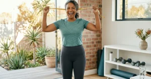 Woman flexing her bicep while holding a tape measure in a home gym